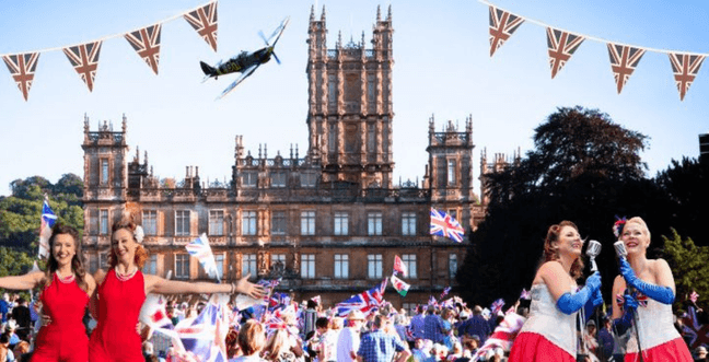 A group of singers in red stands in front of a crowd with Union Jack flags and bunting. The backdrop is Highclere Castle in Newbury