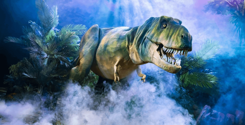 A green t-rex climbs through foliage and fog