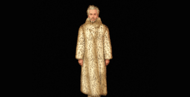 A man with bleach blonde hair stands against a black background, wearing a long leopard print fur coat