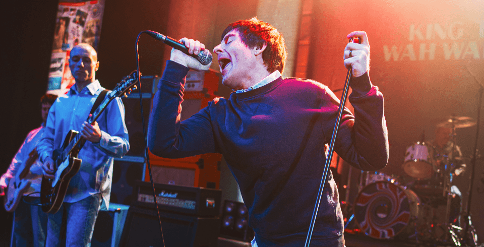 A singer passionately sings into his handheld microphone while holding the mic stand with his other hand