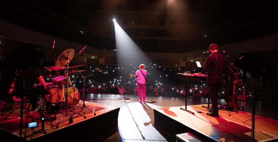 A man with a guitar in the spotlight on stage