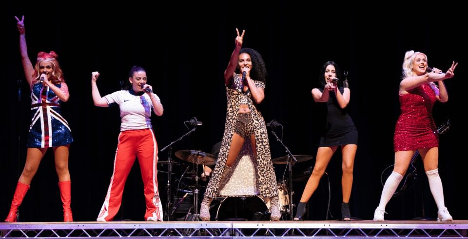 Five performers on stage dressed as spice girls with colourful outfits