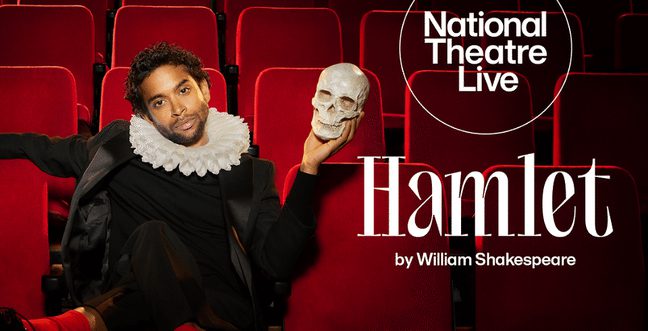 A man in black clothes and a white ruffle neck holding a skull while sitting on red theatre seats.