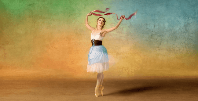 A ballerina in a maid outfit dances on pointe while holding ribbons up in the air