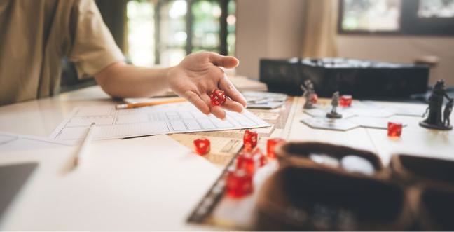 A person rolls a D20 dice across a table