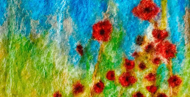 A close up image of a felt image of green grass with blue sky and red poppies.
