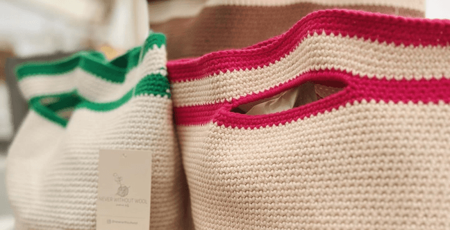 Three cream crochet bags sit next to each other, each has a signature accent colour green, brown and pink