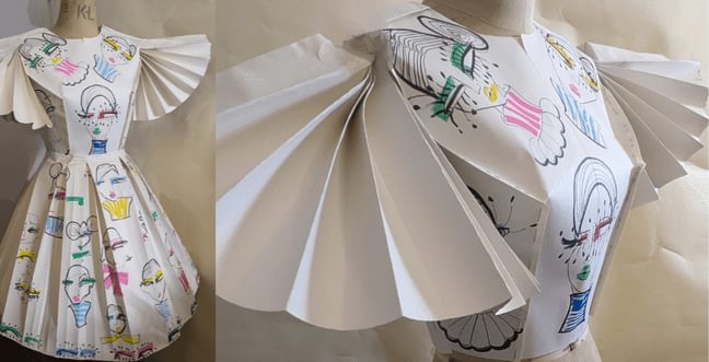 A dress on a mannequin made out of paper with drawings on.