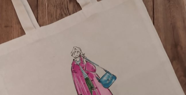 An illustration of a girl on a tote bag in a pink jacket